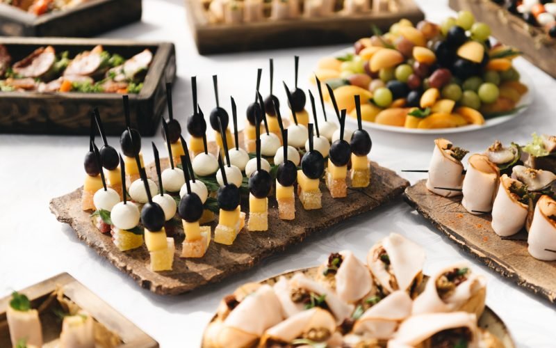 the buffet at the reception. Assortment of canapes on wooden board. Banquet service. catering food, snacks with cheese, jamon, prosciutto and fruit